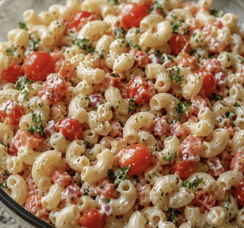 Creamy Amish macaroni salad with diced red pepper in a glass bowl